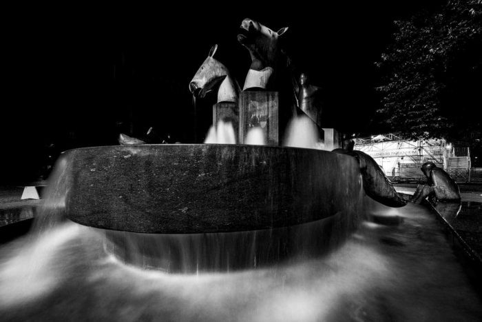 Ein Brunnen mit Pferdeköpfen. Das Wasser fließt seidig