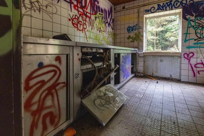 Edelstahlküche an der linken Seite des Raumes, rechts hinten ein Fenster, an den Wänden Graffiti
