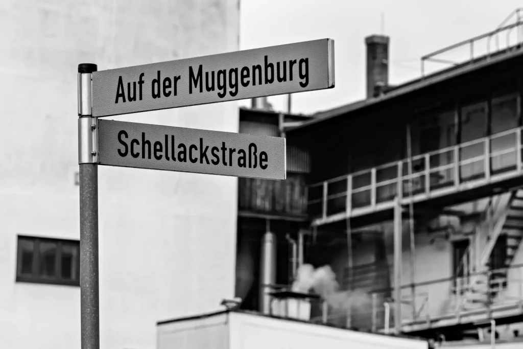 Straßenschild "Auf der Muggenburg" und "Schellackstraße" im Hintergrund eine Fabrik