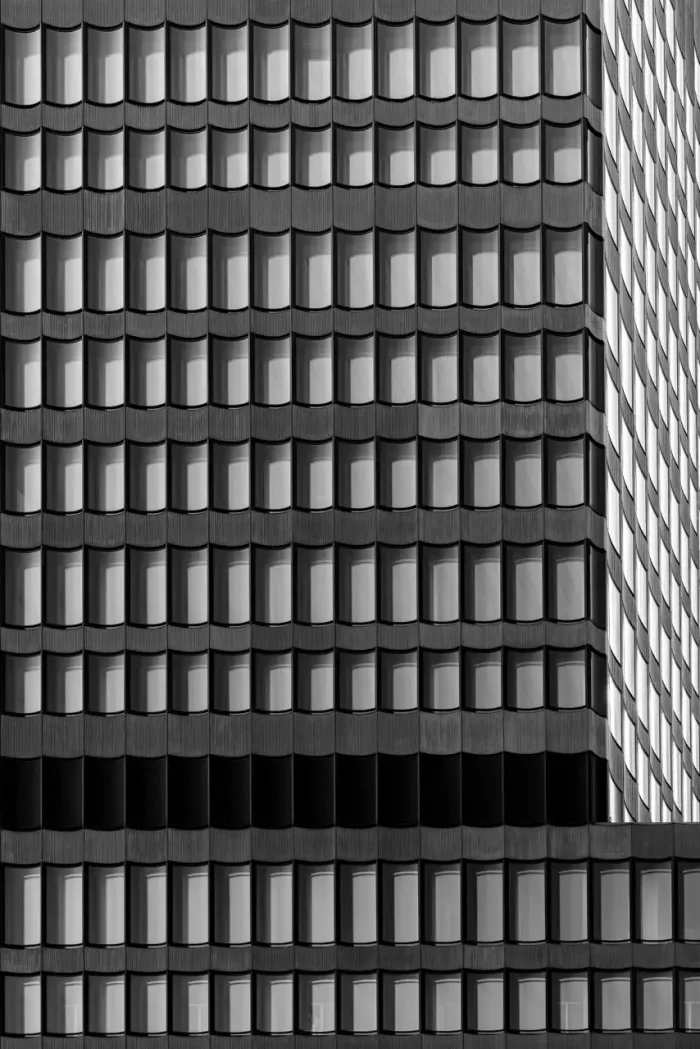 Schwarz-Weiß-Foto der Fassade eines modernen Gebäudes mit einem sich wiederholenden Muster von Fenstern.