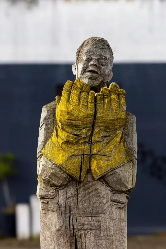 Eine hölzerne Skulptur einer Person mit gelben Handschuhe