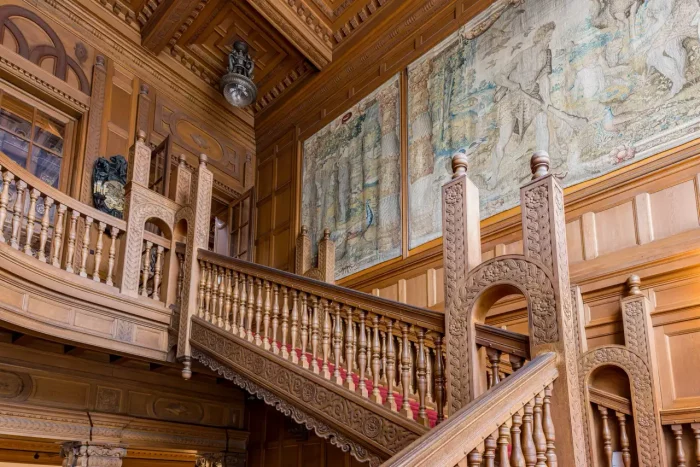 Verzierte Holztreppe mit komplizierten Schnitzereien und zwei großen Wandteppichen.