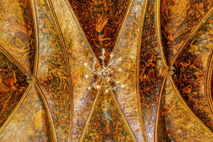 Ornamentale Decke mit komplizierten Gemälden und Mustern, mit einem zentralen Kronleuchter.