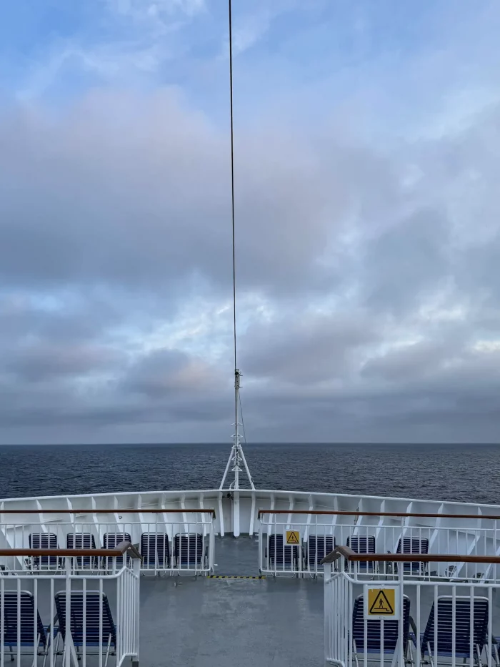 Blick vom Bug eines Schiffes auf das offene Meer unter bewölktem Himmel