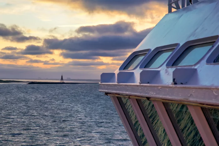Vorderer Teil eines Hurtigruten-Kreuzfahrtschiffs bei Sonnenuntergang über ruhigem Meer