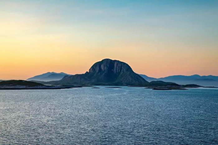 Felseninsel mit markantem Berg vor ruhigem Meer bei Sonnenuntergang
