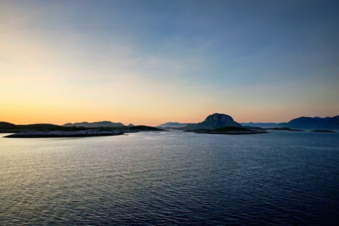 Meer mit kleinen Inseln und Bergen im Hintergrund bei Sonnenuntergang