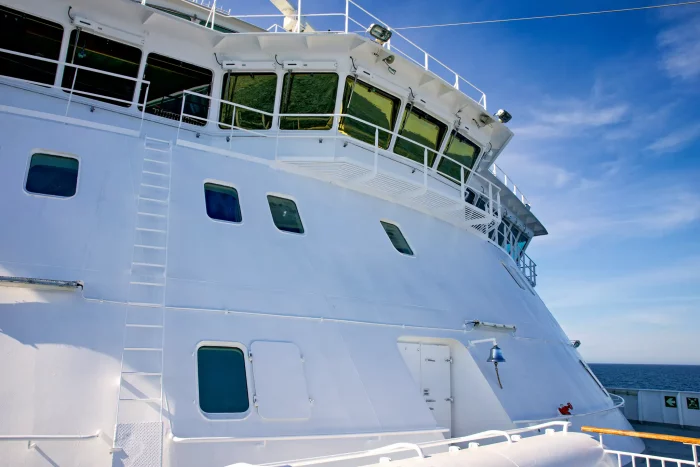 Seitenansicht eines weißen Kreuzfahrtschiffs mit Brücke und Antennen unter blauem Himmel