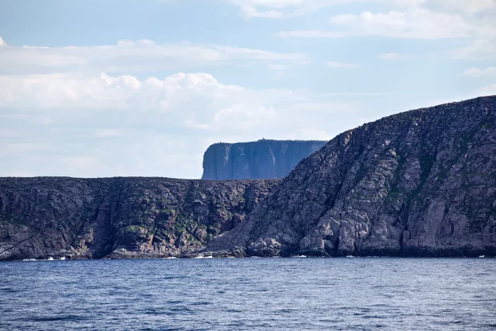 Felsige Küste mit Blick auf das Nordkap, markanter Klippenfelsen am Meer unter bewölktem Himmel