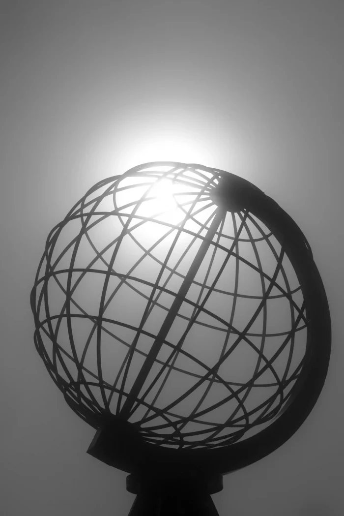 Metallkugel-Skulptur am Nordkap, die die Erde symbolisiert, mit Sonnenlicht im Hintergrund