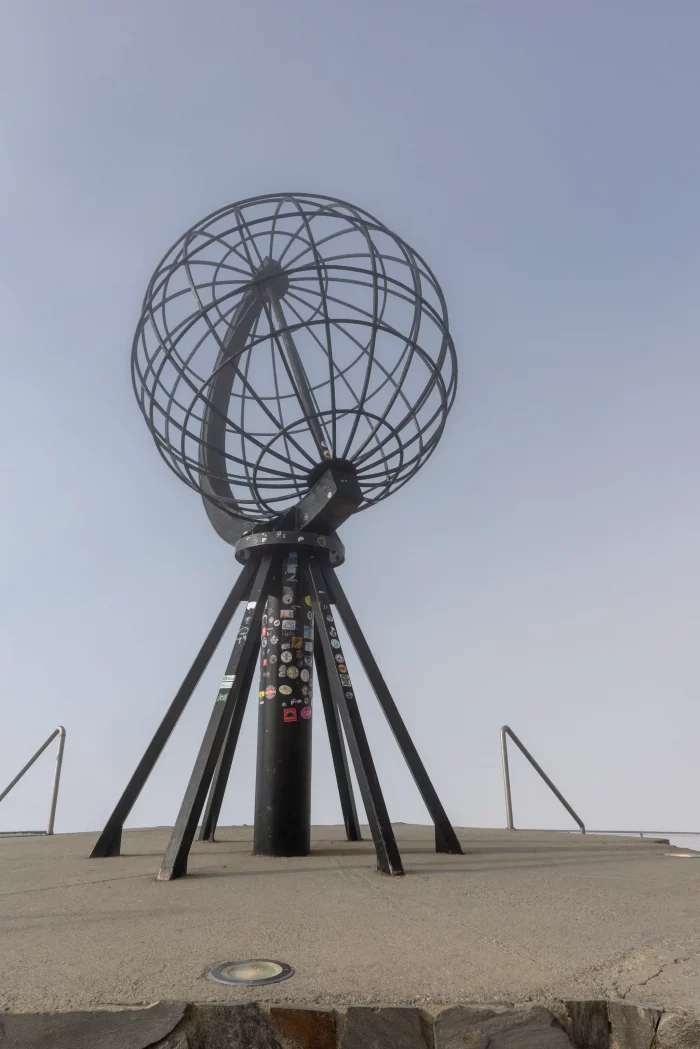 Metallskulptur der Erdkugel auf Stelzen am Nordkap, Norwegen, vor klarem Himmel
