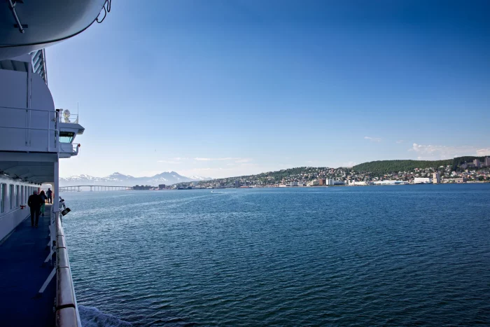Blick vom Deck eines Schiffes auf ruhiges Meer und Küstenstadt unter klarem Himmel