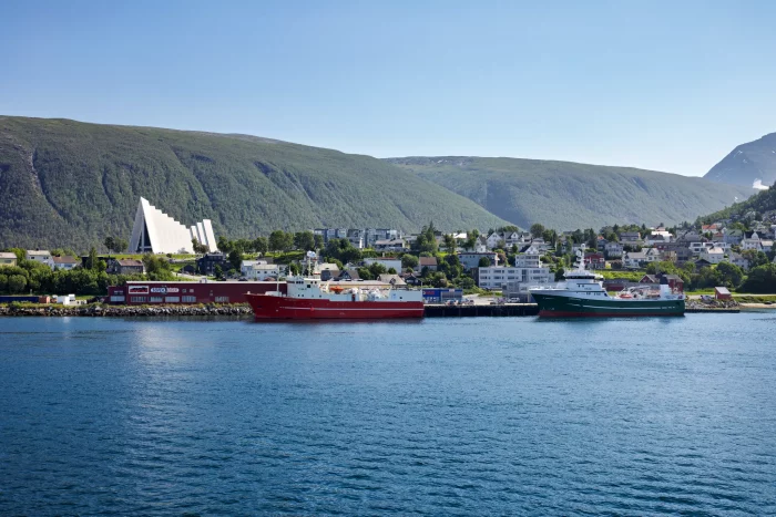 Hafen mit zwei Schiffen vor einer Stadt mit Bergen im Hintergrund