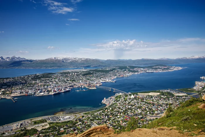 Luftaufnahme der Stadt Tromsø in Norwegen mit Brücke über den Fjord und schneebedeckten Bergen im Hintergrund