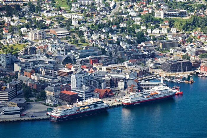 Hafenstadt mit zwei anlegenden Hurtigruten-Kreuzfahrtschiffen und umliegenden Gebäuden und Wohnhäusern