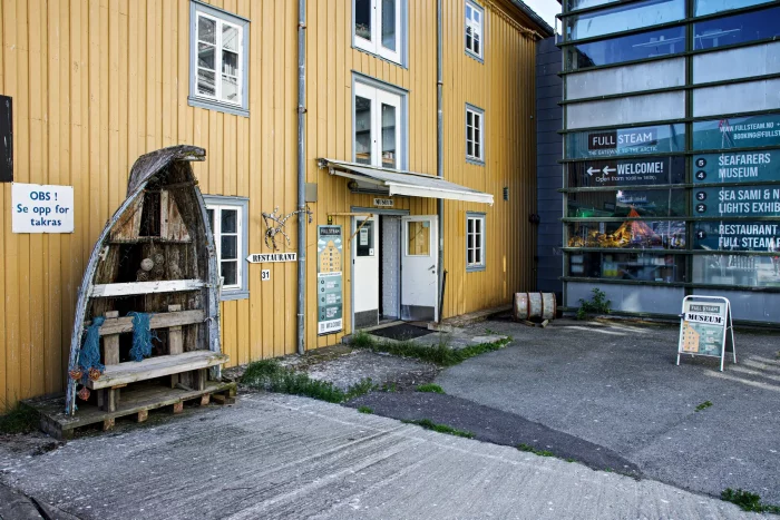 Eingang zum Seafarers Museum mit gelbem Holzgebäude und Schildern, darunter ein altes Boot als Dekoration