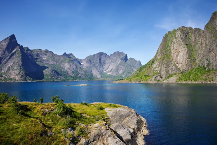 Berglandschaft mit steilen Felsen und klarem Wasser unter blauem Himmel