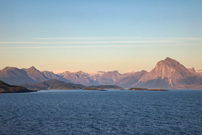 Blick auf ruhiges Meer mit Bergen im Hintergrund bei Sonnenuntergang