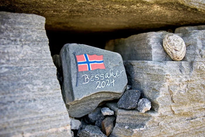 Fels mit norwegischer Flagge und Schrift 'Bessaker 2024' zwischen grauen Felsen