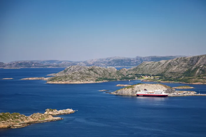 Kreuzfahrtschiff liegt im Hafen. Ruhiges Gewässer zwischen felsigen Inseln unter klarem Himmel