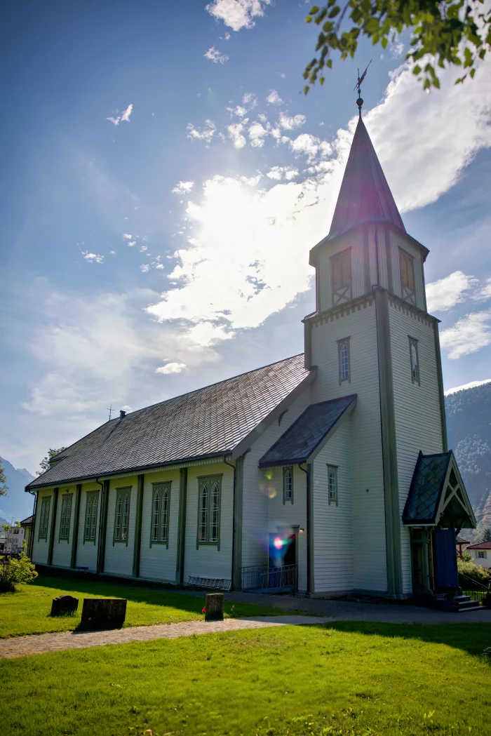 Weiße Holzkirche mit Turm und spitzem Dach bei sonnigem Himmel