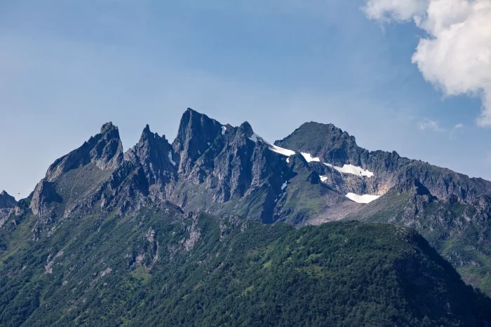 Schroffe Bergspitzen mit vereinzelten Schneefeldern unter blauem Himmel