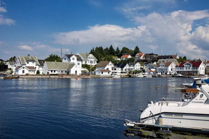 Kleines norwegisches Küstendorf mit weißen Holzhäusern am Wasser und Boot im Vordergrund