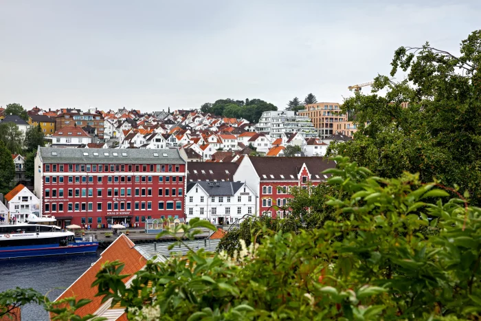 Blick auf Hafen mit roten und weißen Häusern und einem Schiff in einer norwegischen Stadt