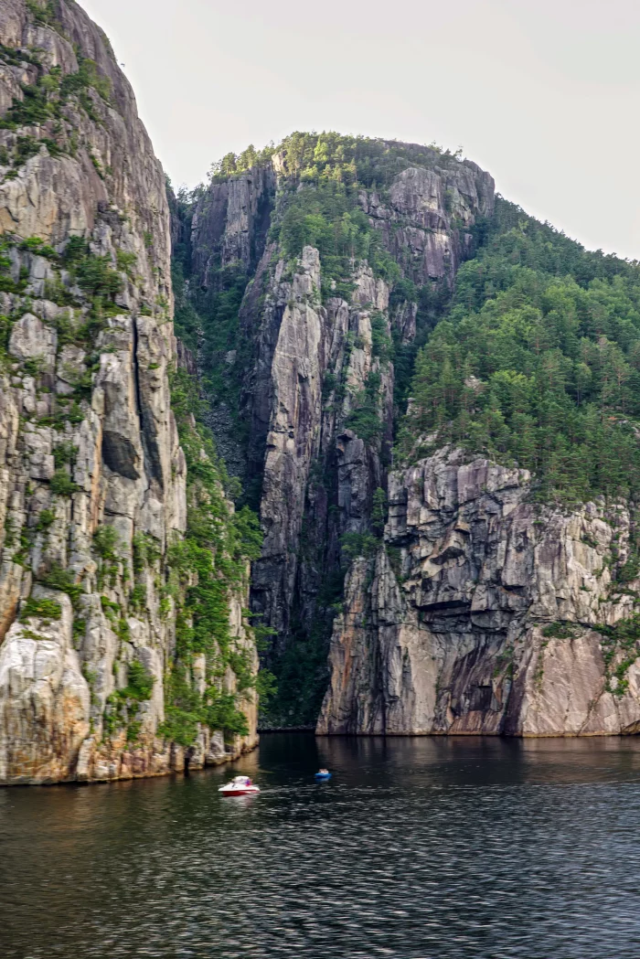 Schmale Wasserstraße zwischen hohen, bewaldeten Felsklippen mit zwei kleinen Booten auf dem Wasser