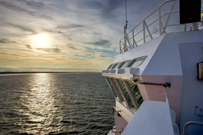 Blick von der Brücke eines Schiffes auf das ruhige Meer bei Sonnenuntergang mit bewölktem Himmel