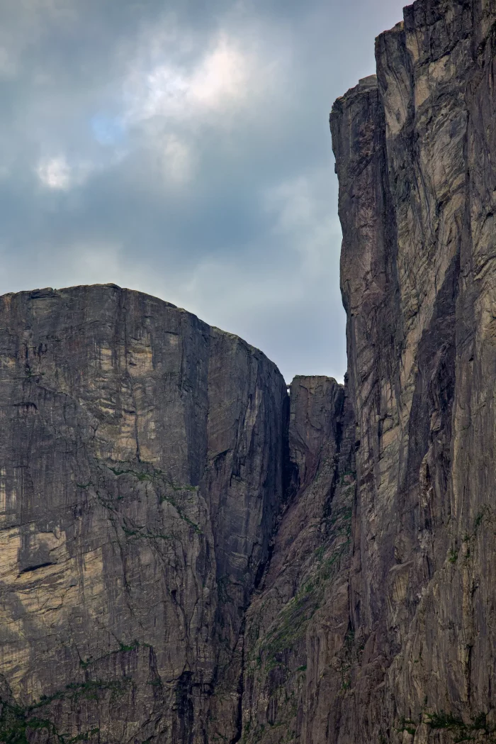 Hohe, steile Felswände mit einer schmalen Schlucht darunter unter bewölktem Himmel