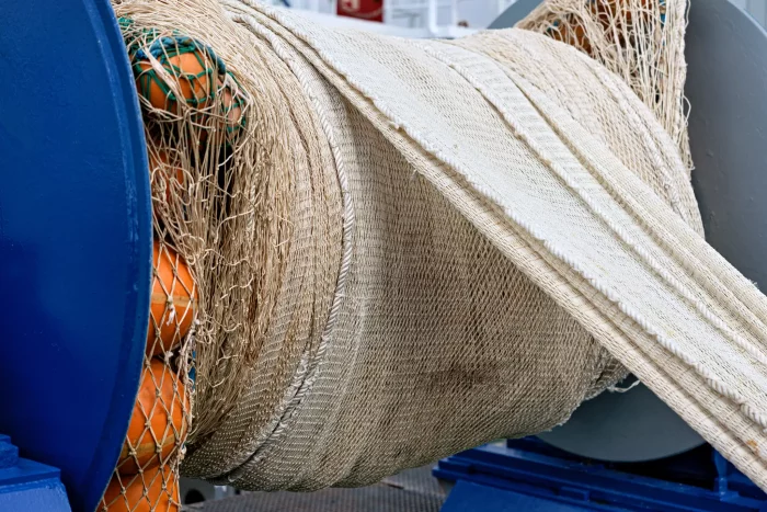 Große Rolle mit beige-farbenem Fischernetz mit orangefarbenen Schwimmern