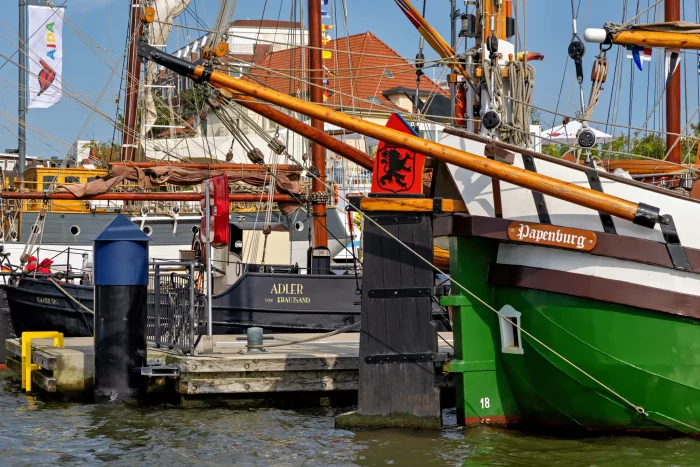 Grünes Segelschiff 'Papenburg' am Hafen mit Holzsteg und weiteren Schiffen im Hintergrund