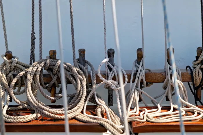 Mehrere dicke Taue sind ordentlich an Holzklampen eines Segelschiffs befestigt