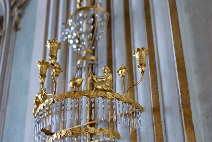 Goldene Kronleuchterverzierung mit sitzender Figur und Blumenmotiven im Schloss Nymphenburg in München