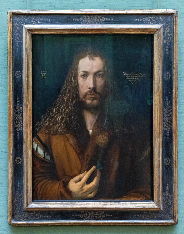 Porträt einer Person mit langen, lockigen Haaren, braunem Mantel mit Pelzbesatz, rechte Hand vor der Brust, dunkler Hintergrund, goldgerahmtes Gemälde.