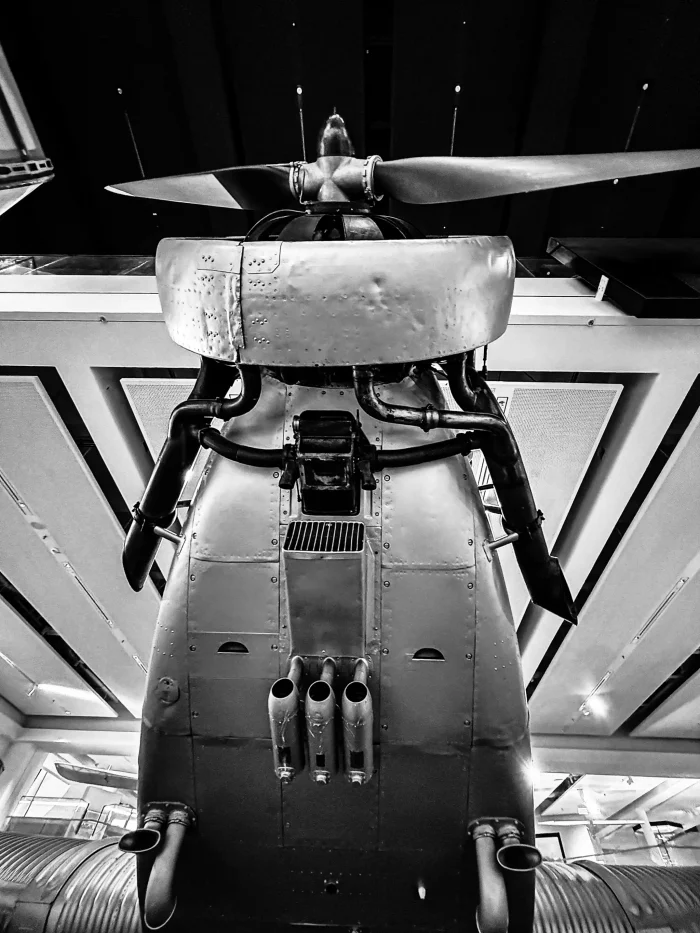 Schwarz-weiße Nahaufnahme eines Flugzeugpropellers mit Motor und Auspuffrohren von unten.