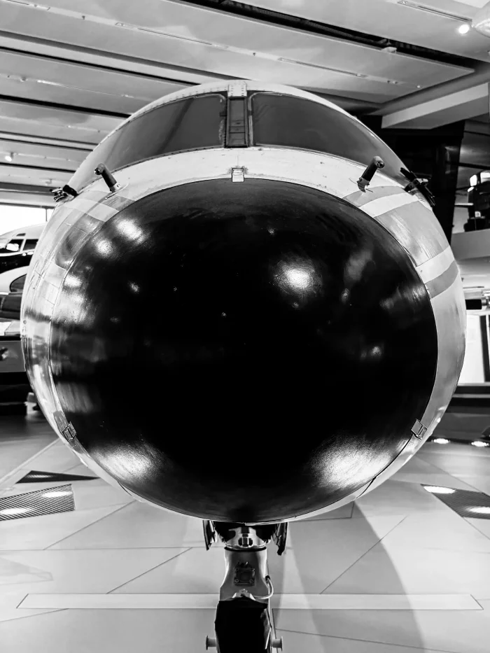 Nahaufnahme der Front eines Flugzeugs mit rundem, schwarz-weiß lackiertem Bug und sichtbarem Fahrwerk.