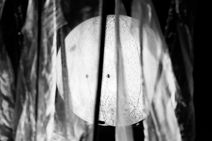 Mond mit sichtbaren Kratern hinter durchscheinenden Stoffbahnen