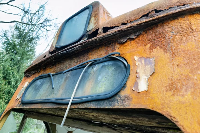 Nahaufnahme des verrosteten vorderen Bereichs einer alten Straßenbahn mit beschädigten Fenstern und abgeblättertem Lack