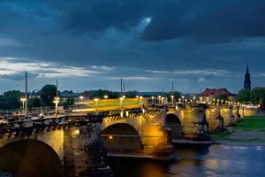Beleuchtete Augustusbrücke über die Elbe bei Nacht, Lichtspur einer fahrenden Straßenbahn.