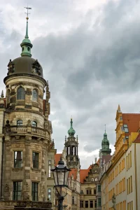 Runder Eckturm mit Kuppel und Türmchen des Dresdner Schlosses vor bewölktem Himmel, dahinter weitere Turmspitzen.