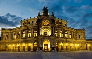 Semperoper abends beleuchtet, klassizistische Fassade mit Figurenschmuck auf dem Giebel.