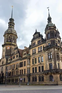 Dresdner Residenzschloss mit Hausmannsturm, Uhr und mehreren Kuppeltürmen, Straße im Vordergrund.
