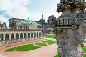 Steinerne Vase mit Maskaron auf Balustrade, im Hintergrund Zwinger Galerie und Gartenanlage.