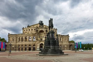 Semperoper mit Reiterstandbild König Johanns auf dem Theaterplatz vor stürmischem Himmel.